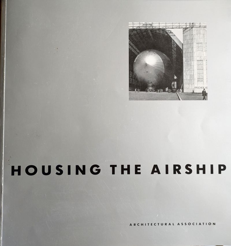 Picture of book cover showing image of an airship's nose emerging from a hangar on a silver background with title in black text